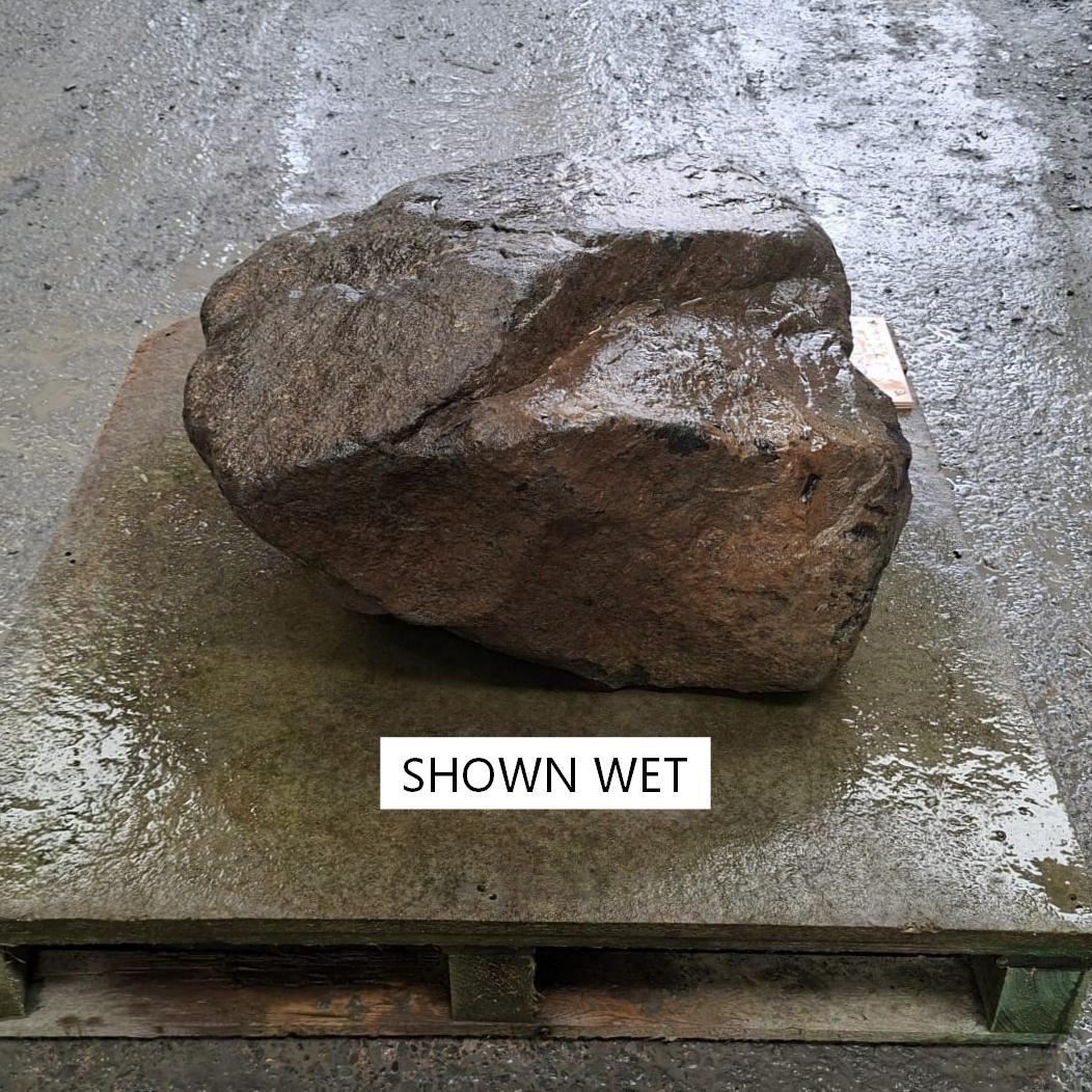 Darekened colours of a wet stone boulder, displayed on a pallet.