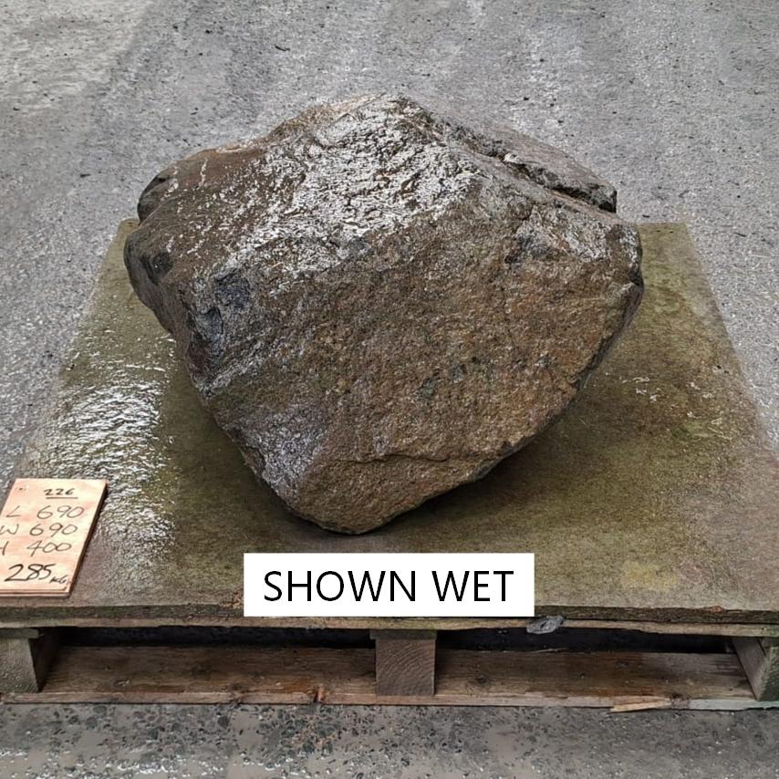 A wet garden stone boulder displayed on a pallet.