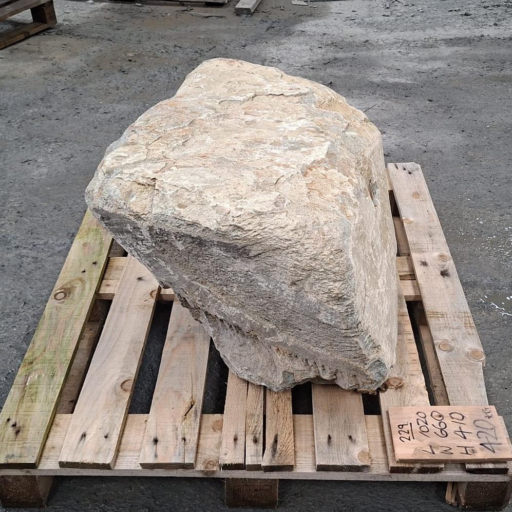 Stone boulder with naturally unique and unusual side profile, with textured surface and natiural colour tones. The boulder sits on a wooden pallet.