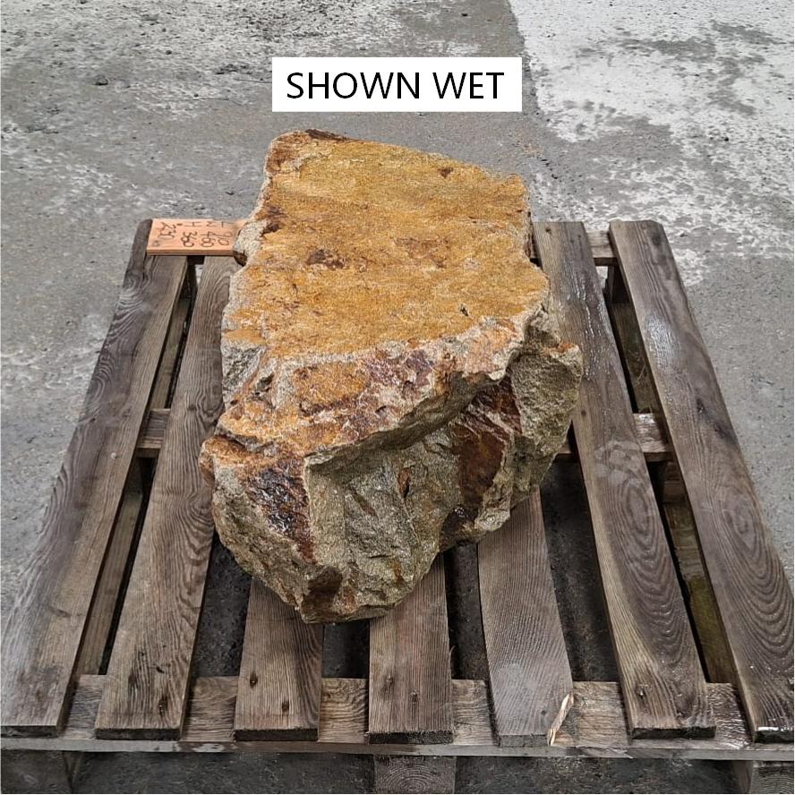 Natural pointed end of a large stone boulder, shown wet.