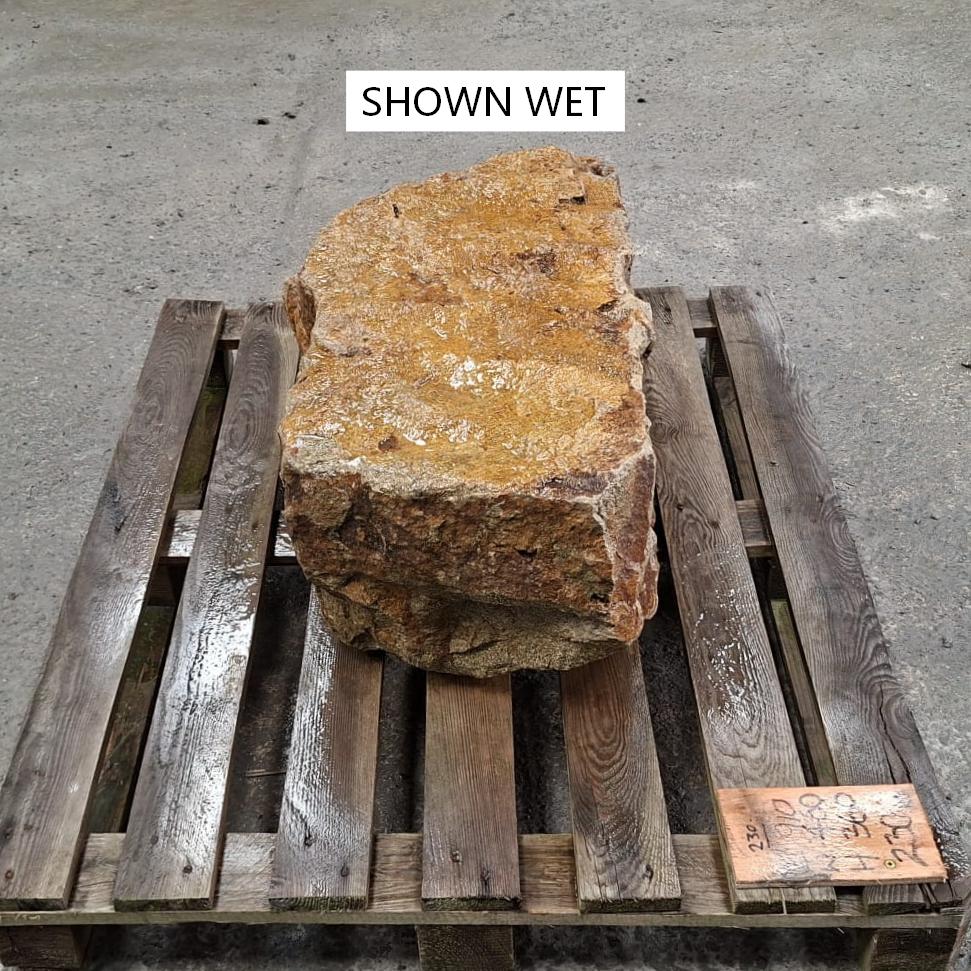 A wet stone boulder with a flat top and natural rough edges.