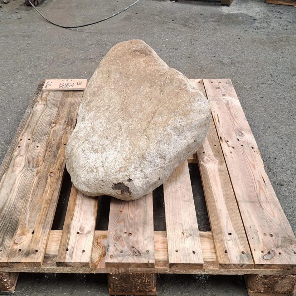 A large natural stone or boulder placed on a wooden pallet outdoors.