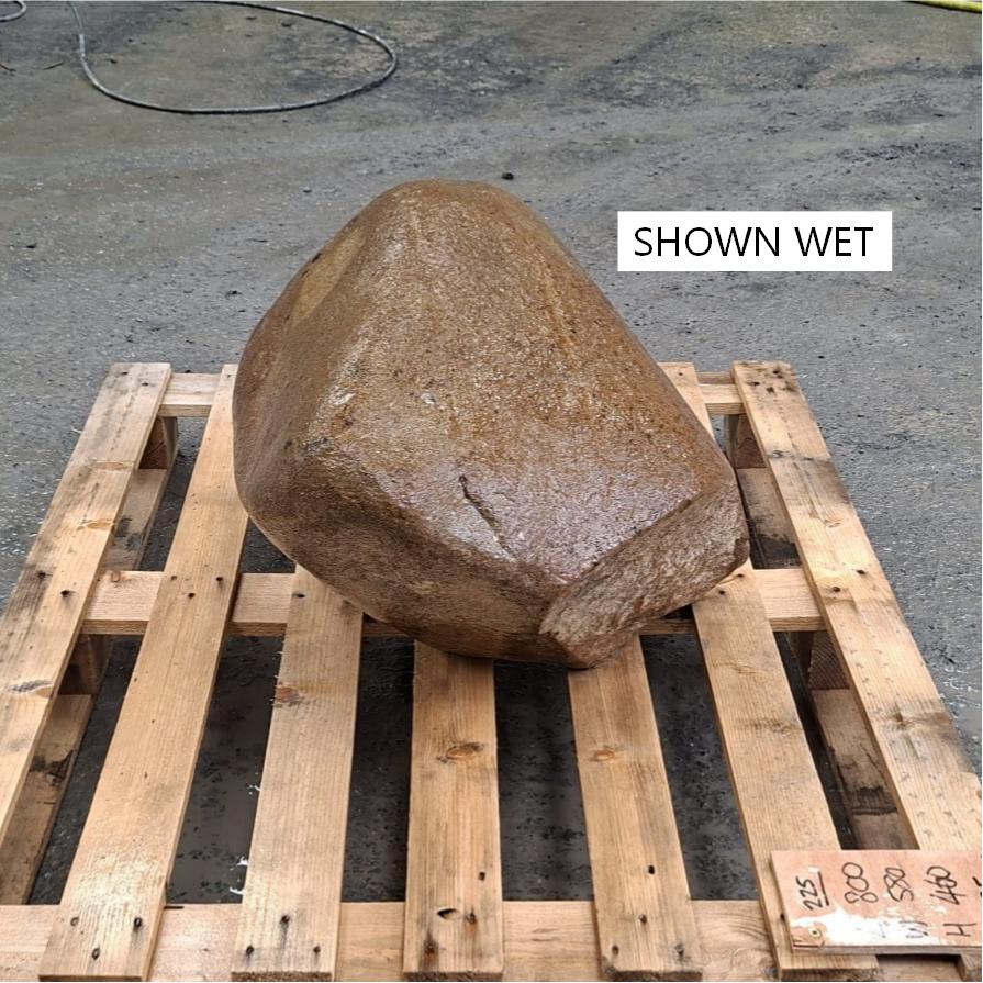 Wet glacial stone boulder with natural irregular shape, sitting on a wooden pallet.