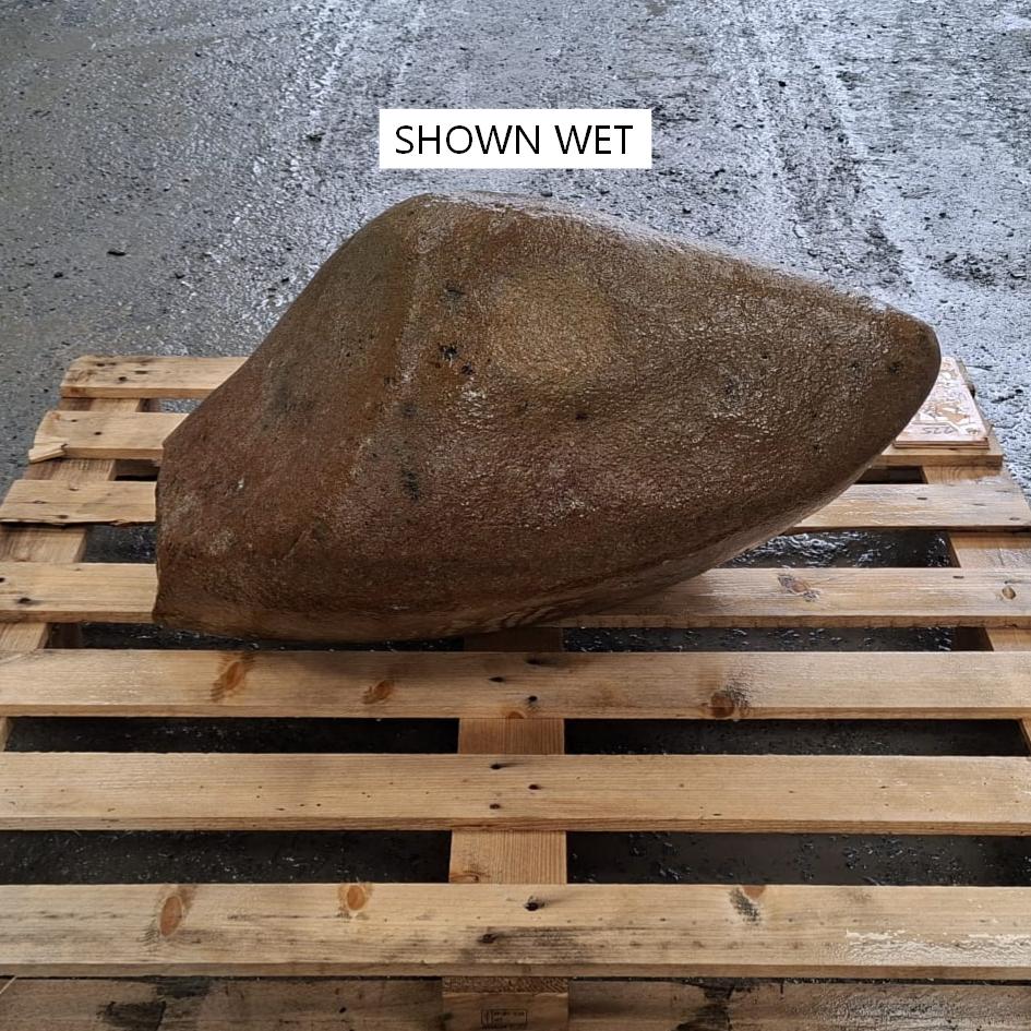 Unique random shaped glacial stone boulder, sitting on a wooden pallet and shown wet.