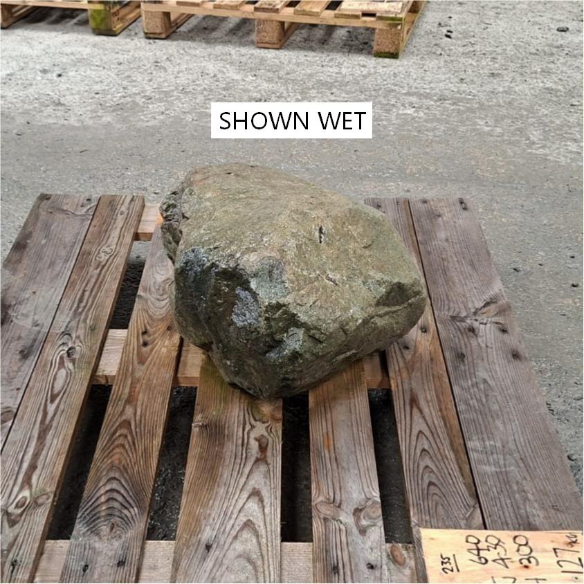 A wet stone boulder with different textures, displayed on a wooden pallet.