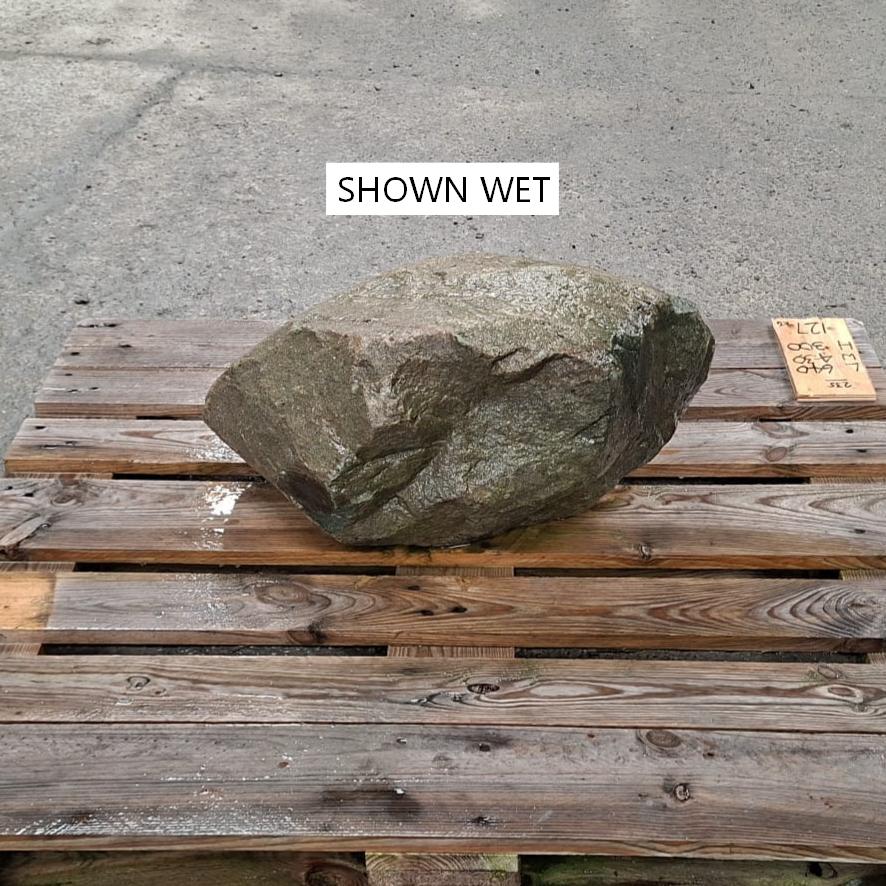 A wet boulder placed on a wooden pallet.