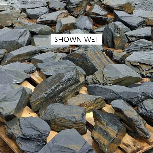 Wet slate stones spread across pallets, showing dark grey and rusty surfaces