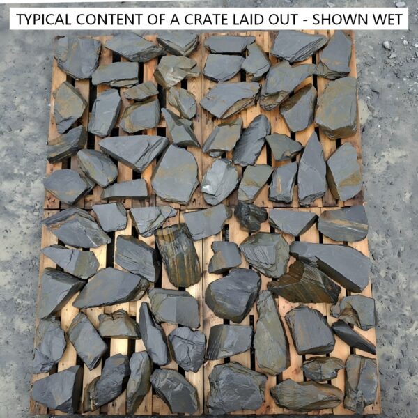 Wet slate rockery stones laid out across pallets, showing darker natural colours