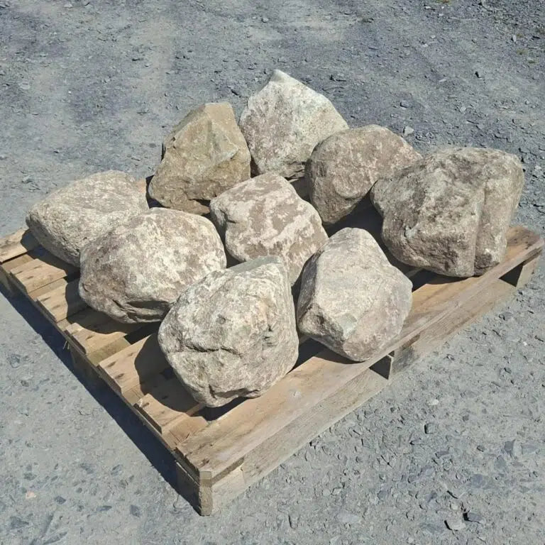 Glacial boulders arranged individually on a pallet in sunlight