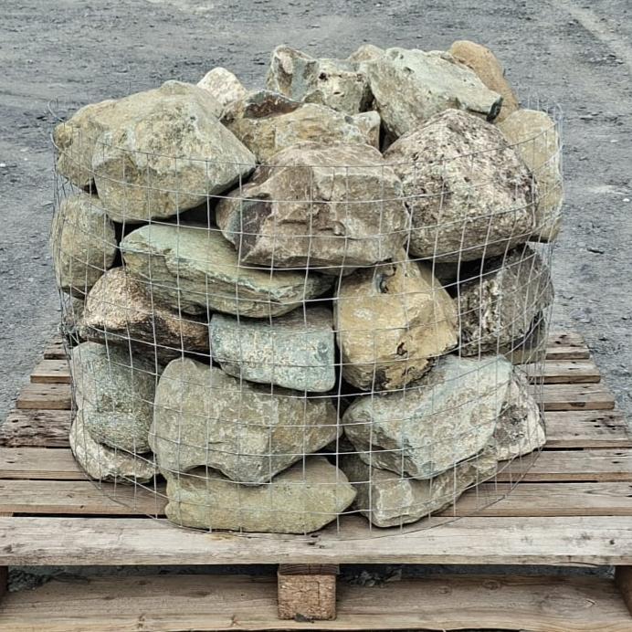 Mixed glacial rockery stones stacked in a wire cage on a pallet