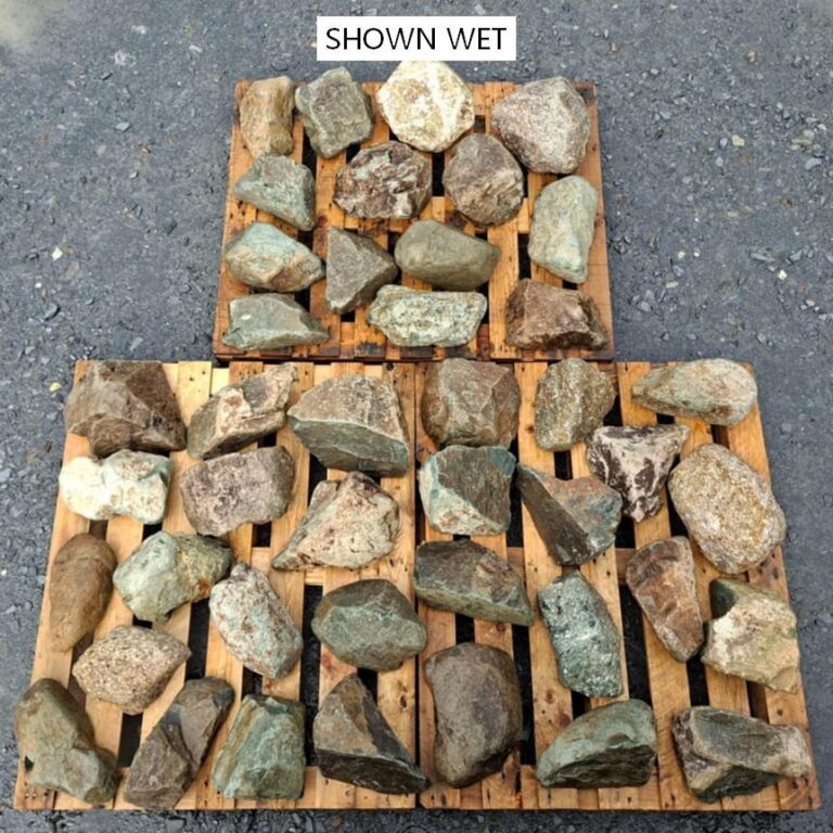 Wet mixed glacial stones spread across pallets, showing natural colour variation