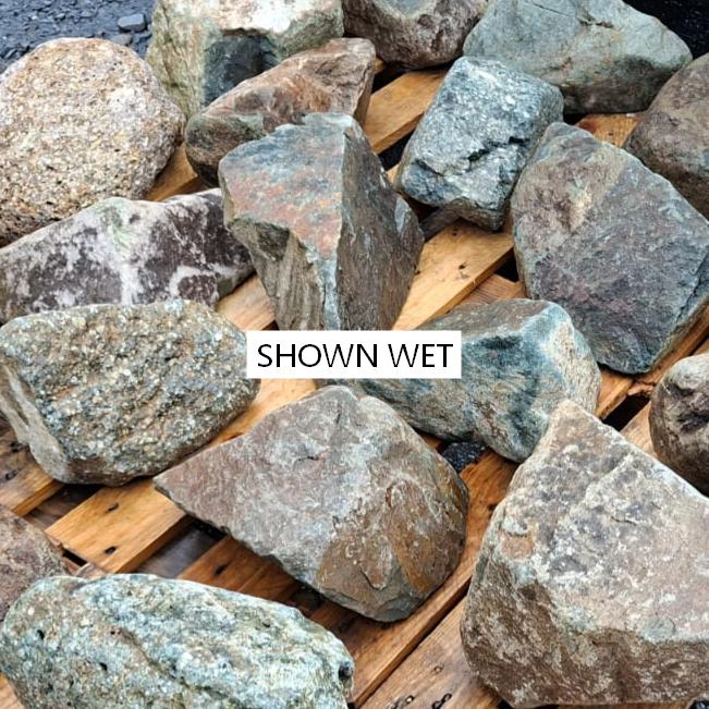 Wet mixed glacial stones showing blue grey faces, pale veins and rusty patches
