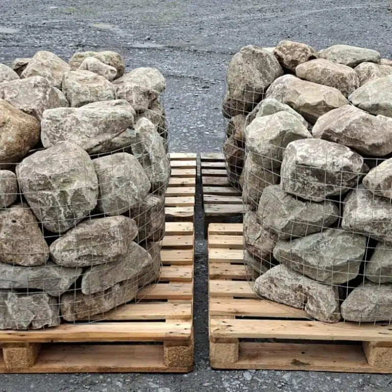 Two pallet cages of glacial rockery stones standing side by side
