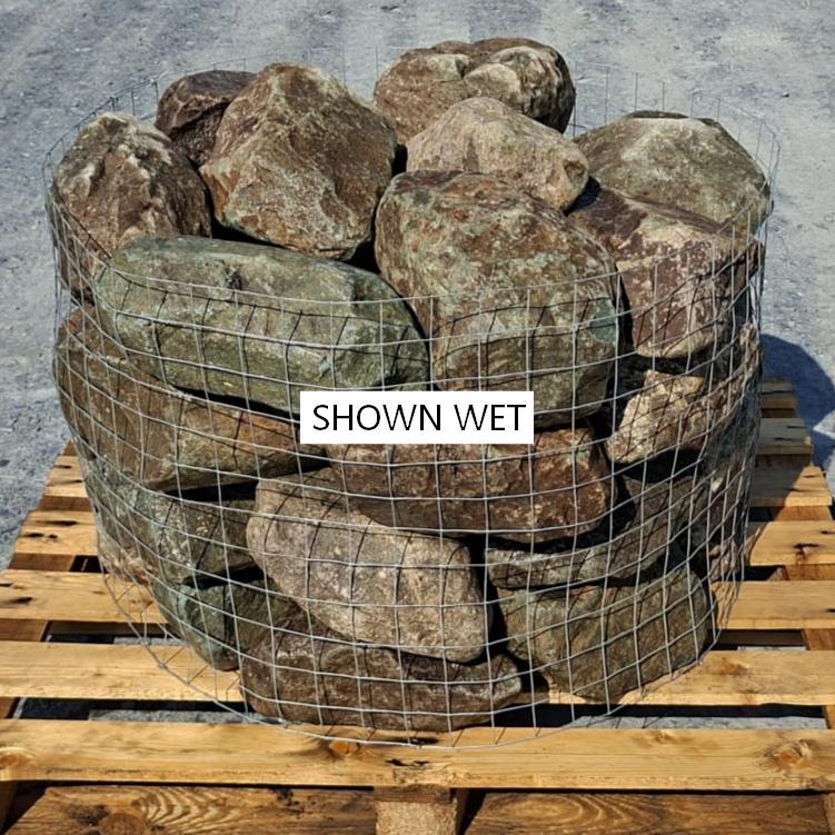 Wet glacial stones stacked behind wire mesh in sunlight