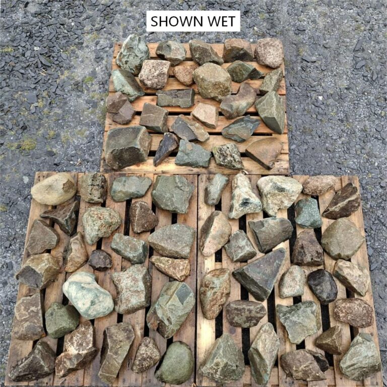 Wet mixed glacial stones spread across pallets, showing varied natural colours
