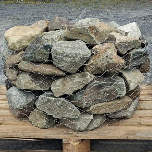 Close-up of stacked mixed glacial stones behind wire mesh
