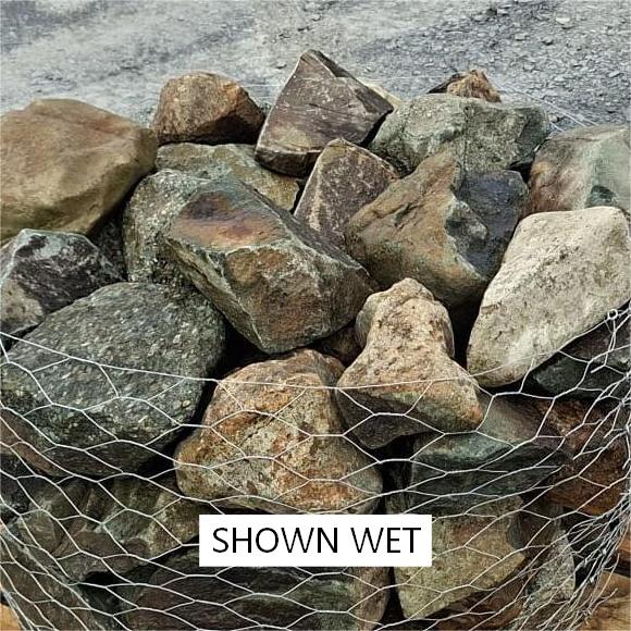Wet mixed glacial stones with dark grey faces and rusty brown markings