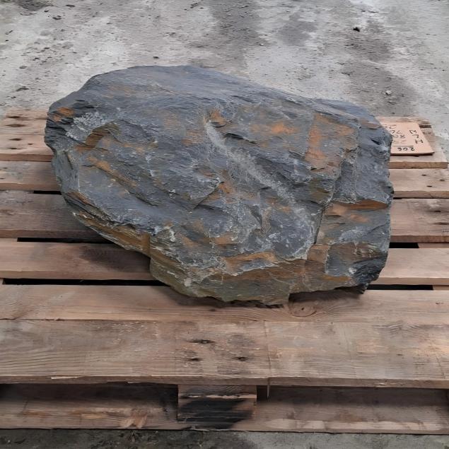 Welsh slate boulder showing an uneven face with orange brown patches