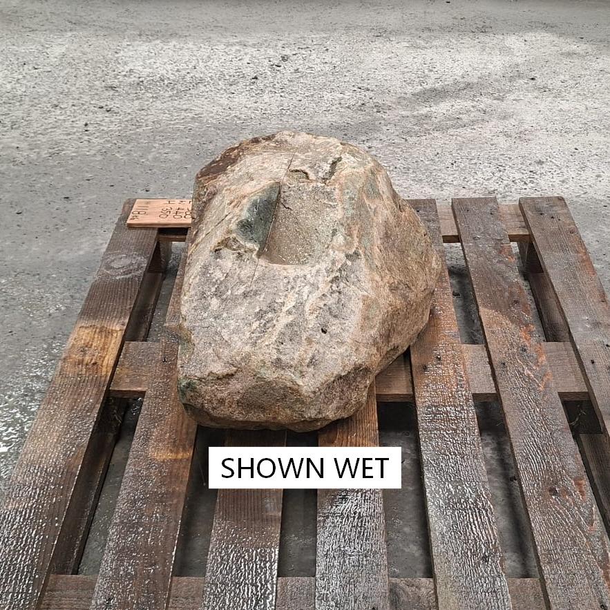 A wet natural glacial boulder with tan and brown colours.