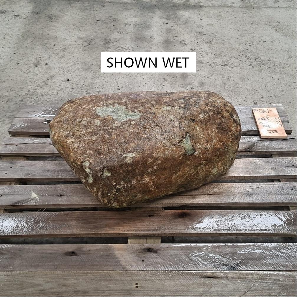 A wet glacial stone placed on a wooden pallet.