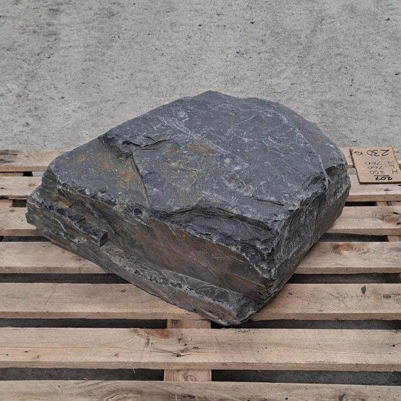 Dark grey slate boulder with a low layered face and rusty brown band
