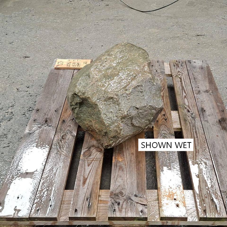 A wet boulder placed on a wooden pallet showing a natural irregular shape.