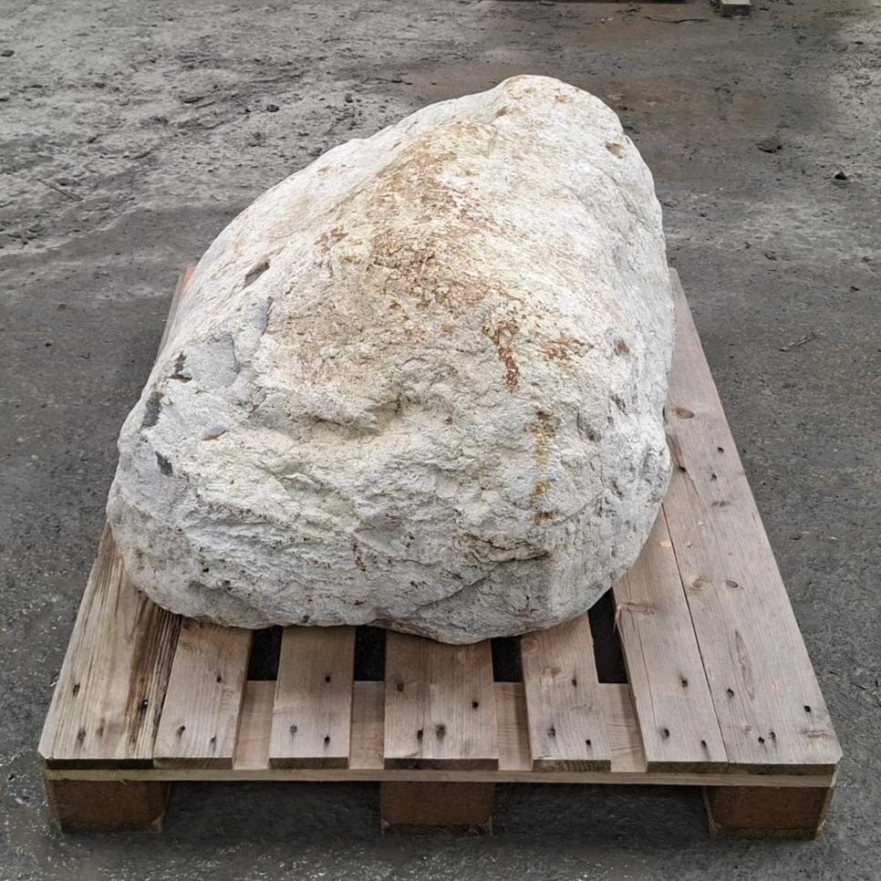 A large irregular white stone or boulder with light tan weathered patches, resting on a wooden pallet.