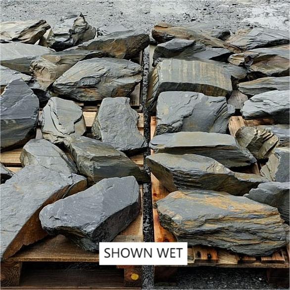Large wet slate stones laid out, showing dark faces and fine layers