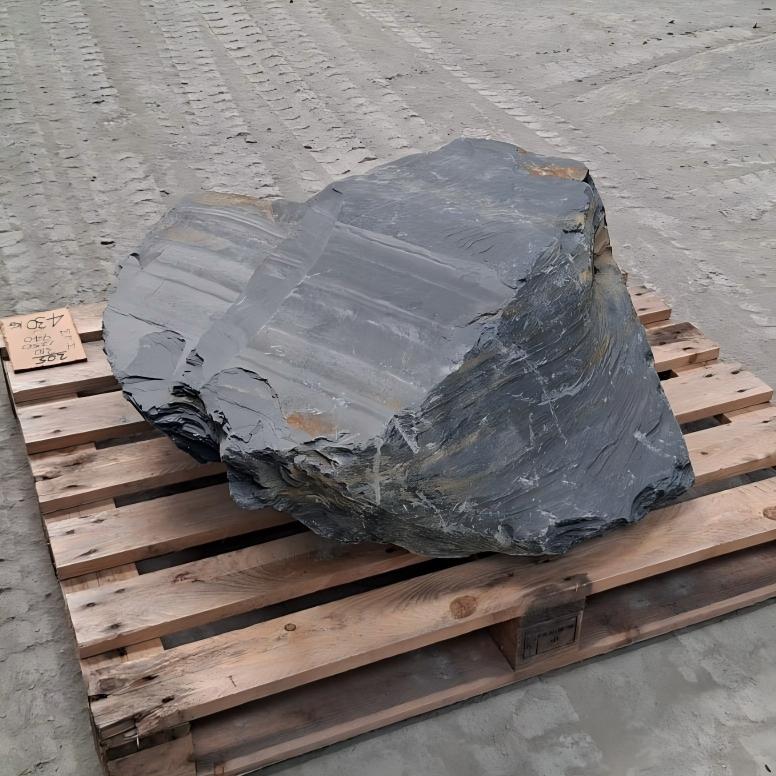 Slate boulder with a smooth sloping face and fine pale lines