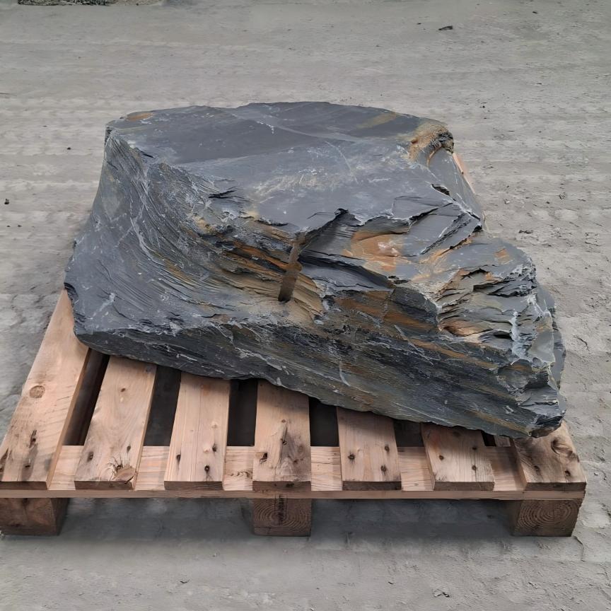 Large Welsh slate boulder with stepped grey layers and rusty bands