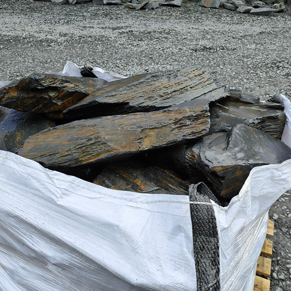 Large Welsh slate rockery stones showing broad layered faces above a bulk bag