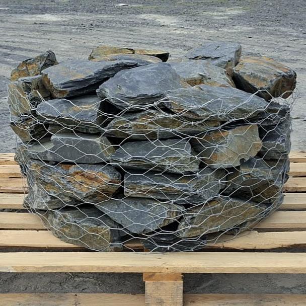 Layered Welsh slate stones stacked inside a wire cage