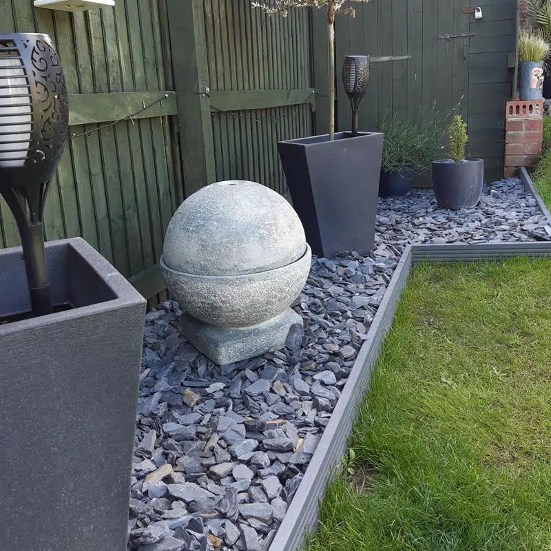 Welsh slate chippings used as garden border ground cover with decorative stone sphere